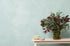 Light blue textured wall with small table holding vase with flowers