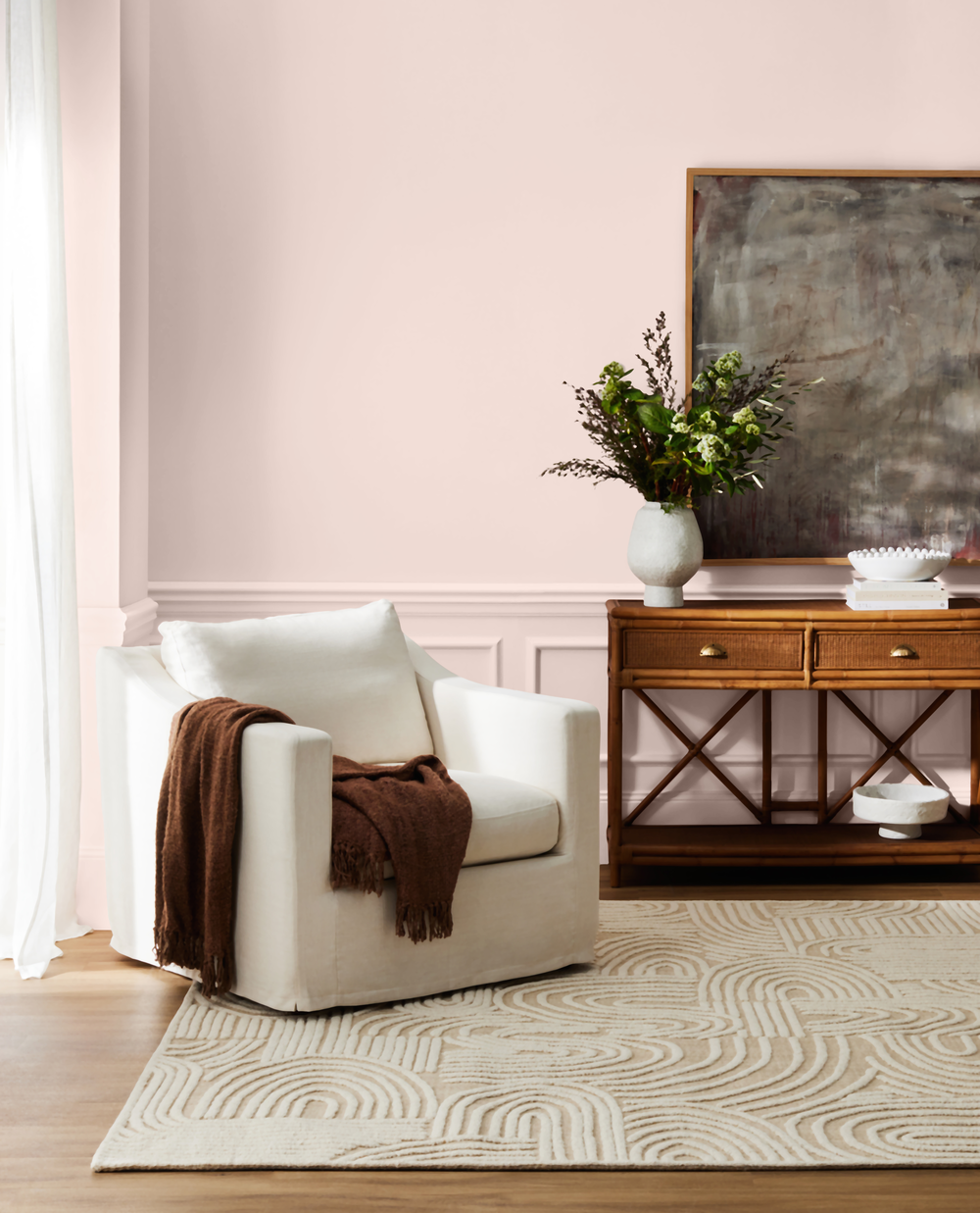 SYDNEY HARBOUR PAINT Co Wall color is PETAL PINK_ Living room with a white armchair, wooden console table, and abstract painting on a pink wall.