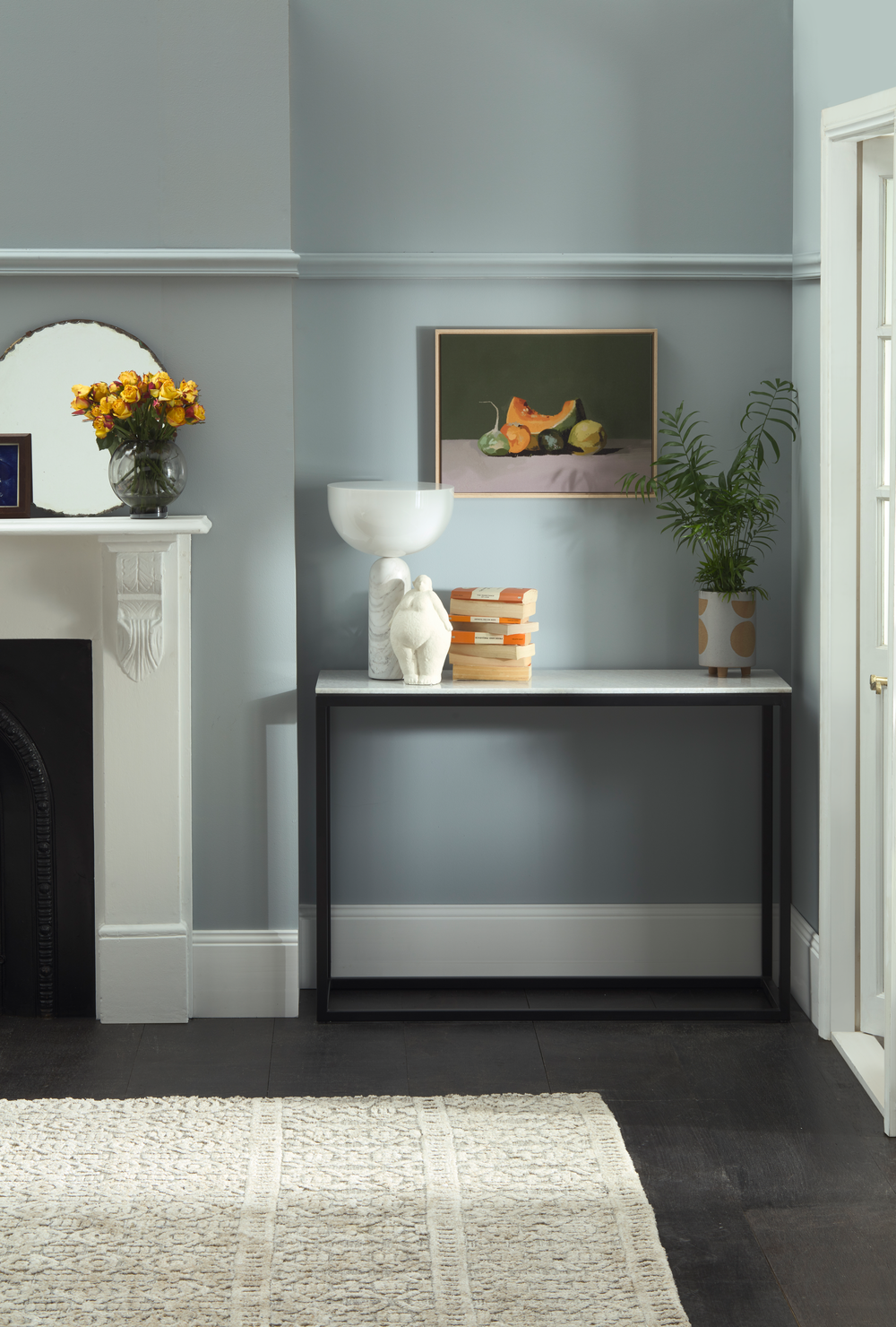 Nook with a small table against a gray wall, featuring decor items. painted in Newport Blue A calming soft grey, with hints of blue and green.