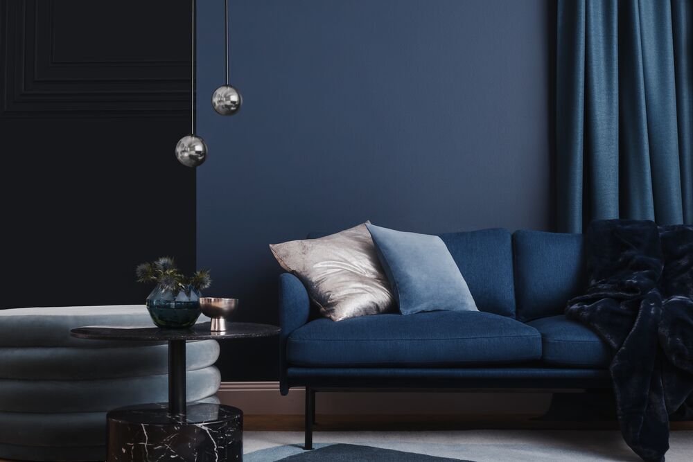 Color is Yacht Race in a Modern Blue in a Modern living room with a blue sofa, dark walls, and decorative elements.