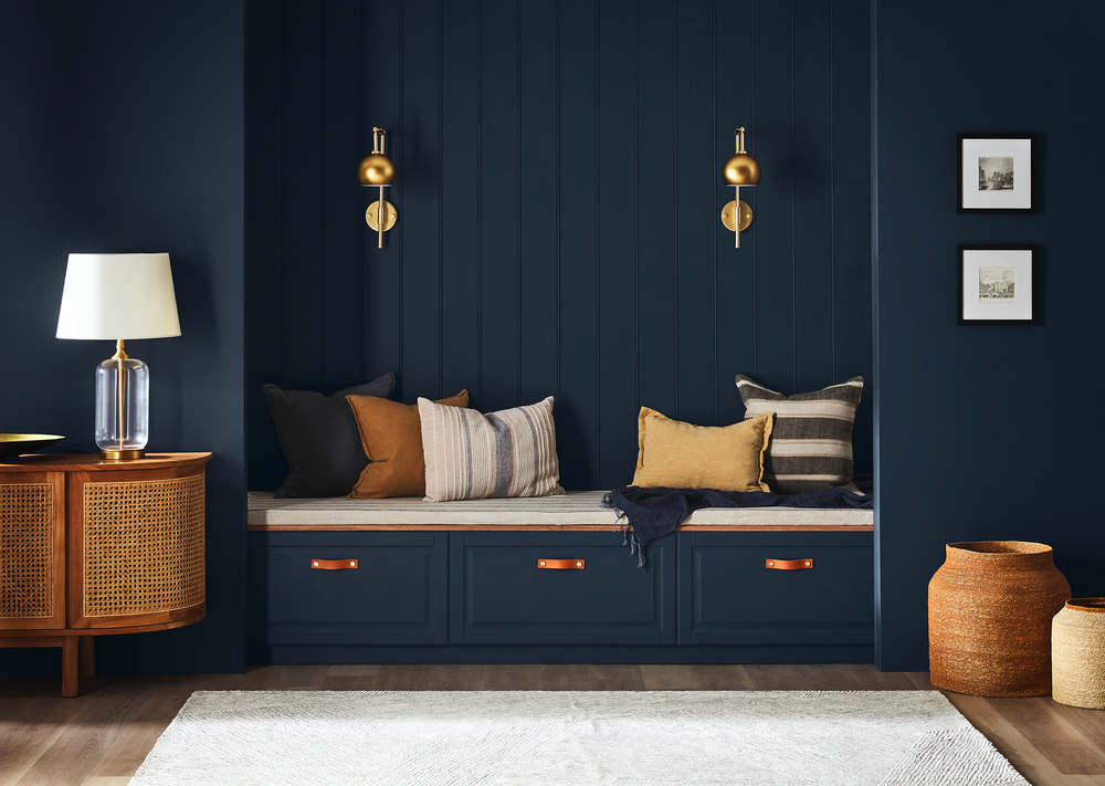 room painted in Yacht Race a blue wall with a built-in bench, decorative pillows, and a wooden side table.