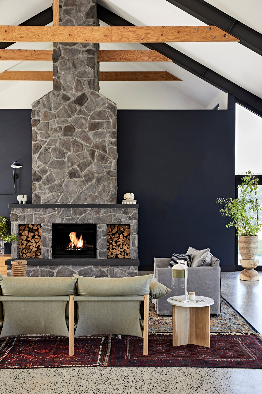 Living painted in color Yacht Race a beautiful blue painted room with stone fireplace, gray sofa, and wooden coffee table.