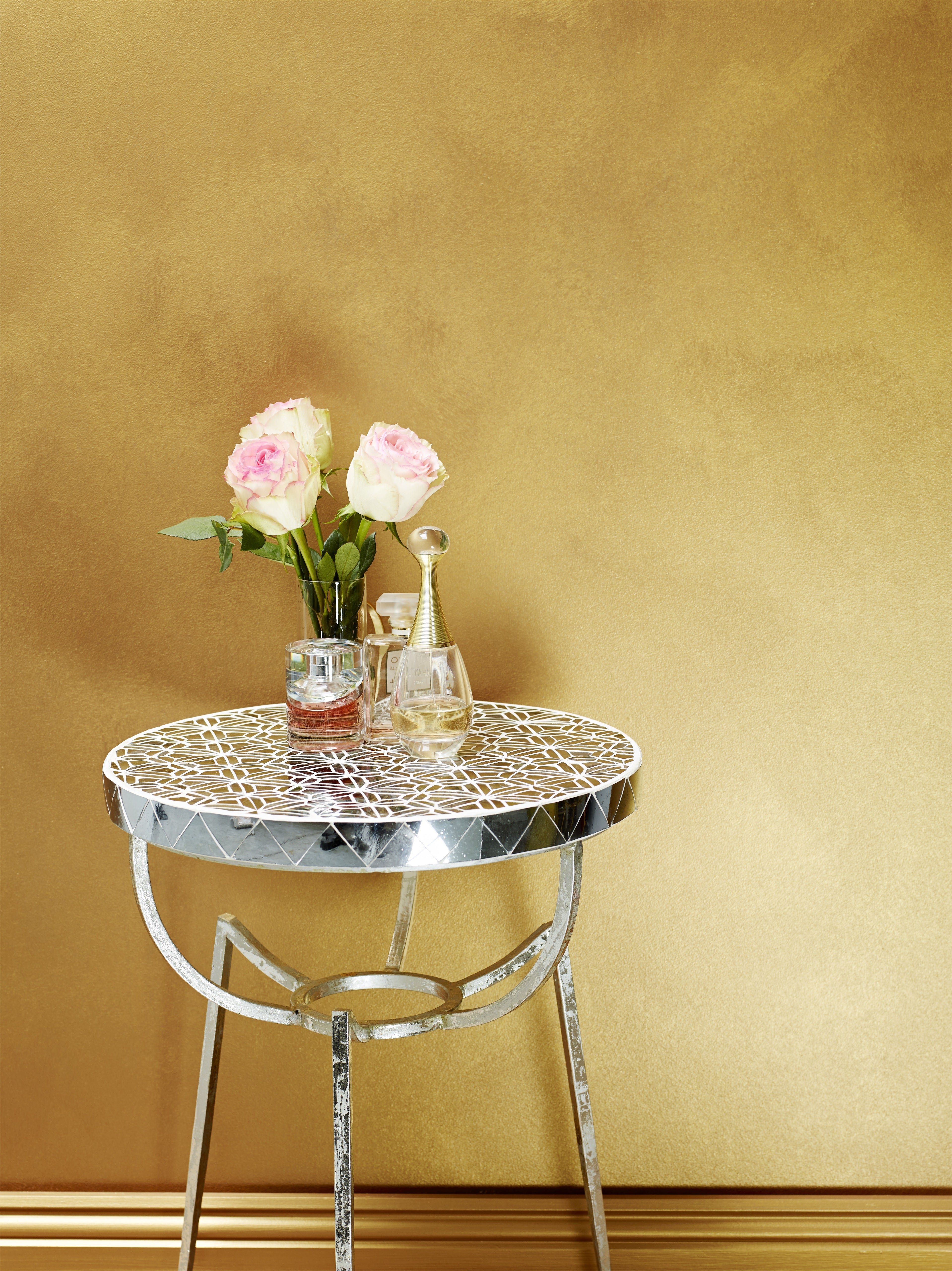 brightly lit LIQUID GOLD PAINT and mirror side table with flowers in a flower vase.